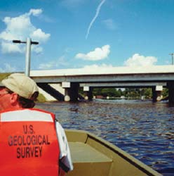 USGS hydrologists approaching a bridge on the Tar River via a boat.