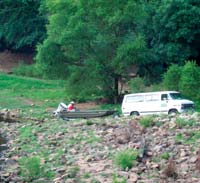 Photograph of USGS van and scientists preparing to load a boat into a body of water.