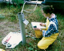Photograph of a USGS scientist recording data from a monitoring well.